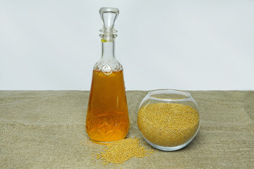 Vegetable, mustard oil for natural nutrition, next to a glass container with mustard seeds.