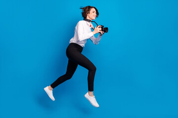 Full length photo of cheerful paparazzi girl hurry fast look empty space isolated on blue color...