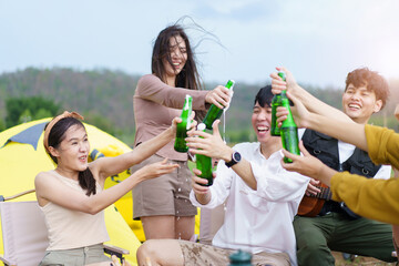 Asian young women and men celebrating with a bottle of a beer together.