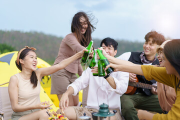 Asian young women and men celebrating with a bottle of a beer together.