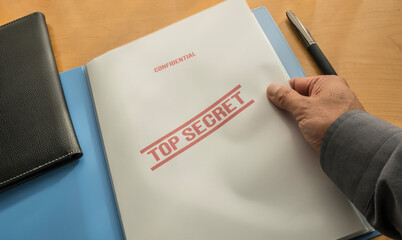 Hand of a man opening an folder with top secret informations