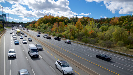 Multi-lane highway traffic in Toronto with autumn leaf colour