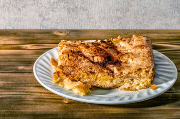 Piece of apple pie Charlotte on a plate on a wooden table.	