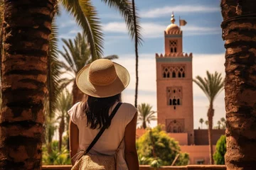 Foto op Canvas Back view of asian woman wearing hat looking at mosque in morocco, rear view of a Woman looking at Koutoubia mosque minaret-Tourism in Marrakech, Morocco, AI Generated © Iftikhar alam