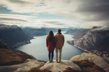 Couple standing on the edge of a cliff and looking at the fjord, rear view of Couple family traveling together on cliff edge in Norway, AI Generated - obrazy, fototapety, plakaty