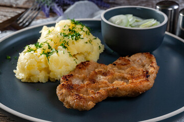 Pork chop served with mashed potatoes and cucumber salad.