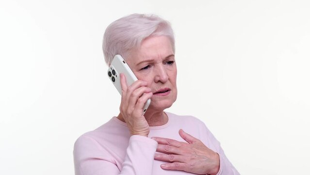 Distressed mature woman engages in a conversation on phone. Her furrowed brow and tense expression reveal emotional state, capturing a moment of deep concern and frustration.