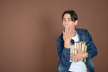 Young man and study. Funny attractive guy posing on a brown background.