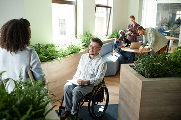 Businessman with disability talking to his colleague during meeting in office hall