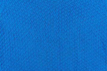 Texture and pattern of a knitted blue wool sweater. Background of warm handmade wool fabric.