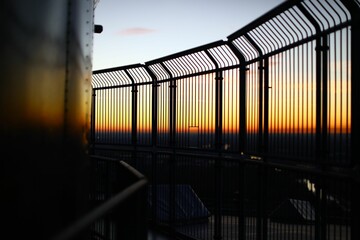 Fototapeta premium Sunset view from behind metal fence in a tower