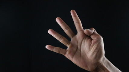 Male hand gesture number four closeup isolated on a black background