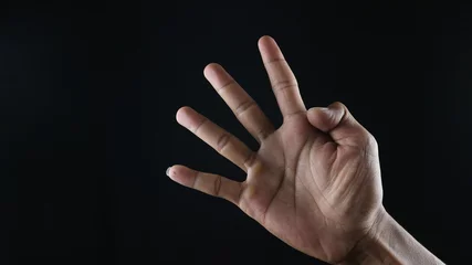 Fotobehang Male hand gesture number four closeup isolated on a black background © Aufa Fahmi 