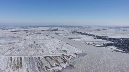 Fototapeta na wymiar Aerial view of a white snowy field with a frozen lake