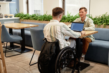 Colleagues having meeting in cafe, they sitting at table with laptop and discussing online presentation