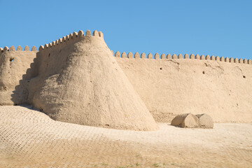 Fragment of an ancient defensive wall with a tower on a sunny day. Inner city of Ichan-Kala. Khiva, Uzbekistan