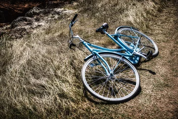A blue bike laying on the ground in the grass © theartofphoto