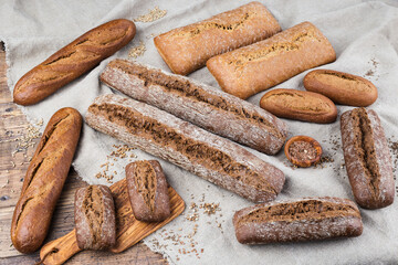 Assortment of different types of rye bread, baguettes on rustic wooden background