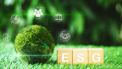ESG icon concept circulating earth globe with ESG text on wooden dices in green natural garden...
