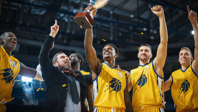 Multiethnic Basketball Players Celebrate Championship Victory with Hugs, Jumping, And Holding the Trophy. Exclusive Joyful Sports Action on Live TV and Pay Per View Internet Streaming Concept.