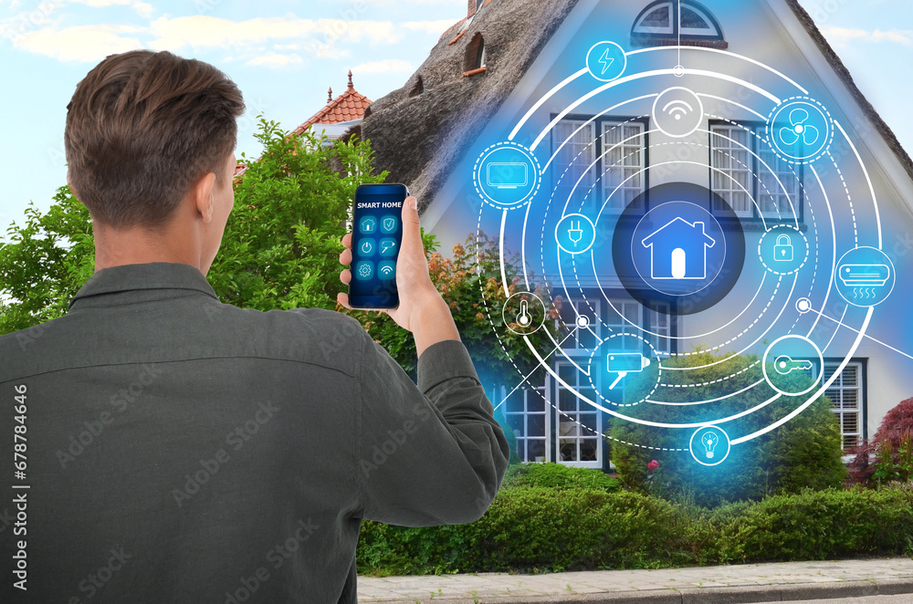 Poster man using smart home control system via application on mobile phone outdoors. scheme on house
