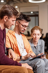 Vertical image of colleagues using tablet pc at work while sitting in office