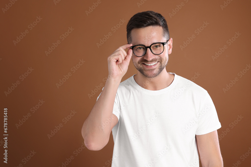 Poster portrait of happy man in stylish glasses on brown background. space for text