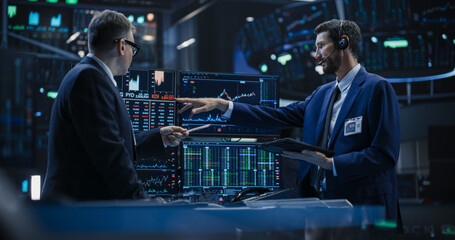 Team of Two Handsome Stock Exchange Brokers Using Tablet Computer, Chatting About the Asset...