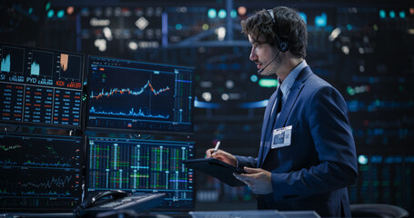 Portrait of a Young Man Working in an International Stock Exchange Company: Professional Using a Tablet Computer, Monitoring Financial Markets, Communicating with Corporate Business Partners - obrazy, fototapety, plakaty