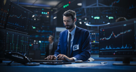 Adult Stock Exchange Broker Working on a Desktop Computer with Real-Time Stock Information,...