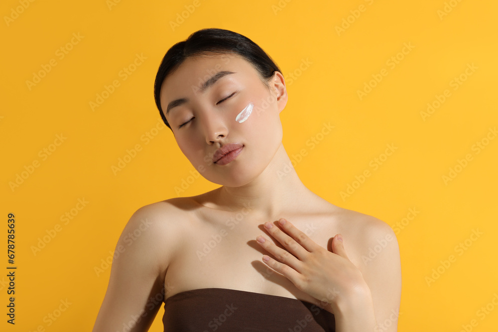 Canvas Prints Beautiful young woman with sun protection cream on her face against orange background