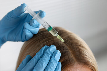 Trichologist giving injection to patient in clinic, closeup