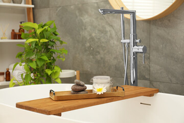 Shelving unit and wooden tub tray with different spa products in bathroom