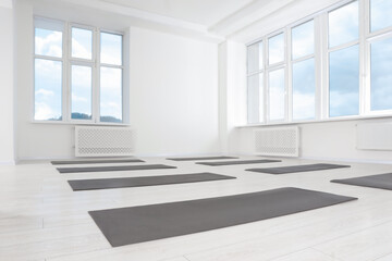 Spacious yoga studio with exercise mats and big windows, low angle view