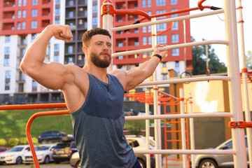 Man showing biceps at outdoor gym on sunny day
