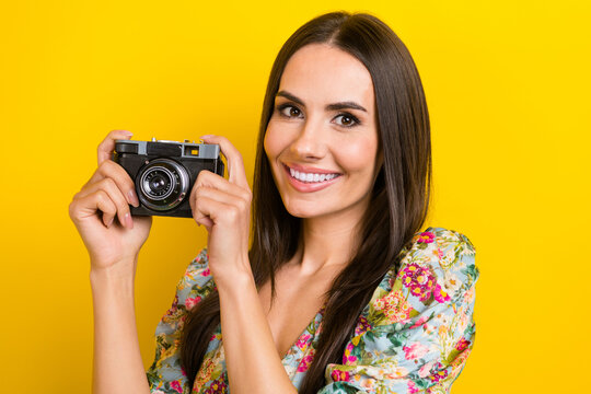 Portrait of lovely positive woman with long hairstyle wear stylish dress hold camera make photo isolated on yellow color background
