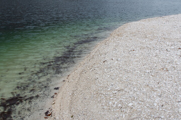 The shore of a lake with a pebble and sand.