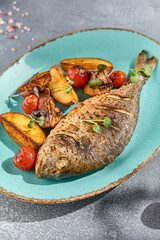 A closeup vertical frame capturing the sumptuous textures and colors of a grilled Dorada fish dish. Served with potatoes, mushrooms, and cherry tomatoes for a balanced meal
