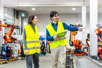Engineer explaining and pointing robotic welding process to a women