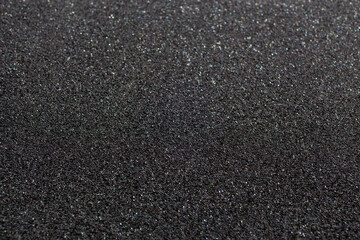 Black foam rubber. Closeup full-frame macro background with selective focus and shallow depth of field. - obrazy, fototapety, plakaty