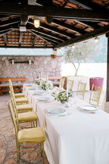 Golden chairs stand near a long festive table under a canopy in the garden