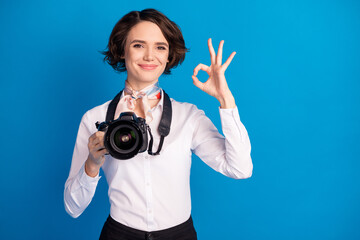 Photo of pretty satisfied girl arm hold camera fingers show okey symbol isolated on blue color background