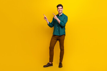 Fototapeta premium Photo of positive attractive man dressed green stylish clothes presenting novelty empty space isolated on yellow color background