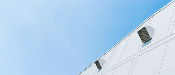 White industrial building with small vents against clear blue sky. Minimalist architecture.