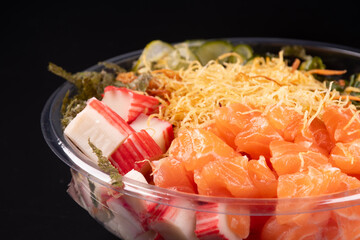 bowl of oriental japanese food and kani isolated on white background raw salmon close up with pair of chopsticks black background