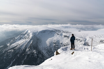 Active people in nature. A male tourist enjoys the view while walking through the snow-capped mountains. Karpacz, Sniezka, Poland