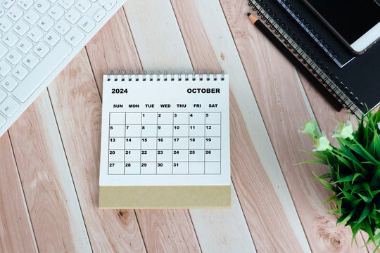 White October 2024 calendar on office wooden desk.