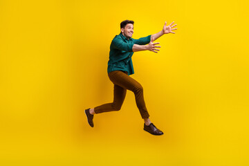 Full length profile side photo of overjoyed man wear stylish clothes open hands running empty space isolated on yellow color background
