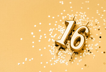 16 years celebration festive background made with golden candle in the form of number Sixteen lying...