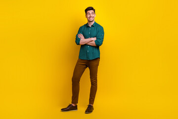 Fototapeta na wymiar Full length photo of responsible worker nice man standing with crossed arms watching up empty space isolated on yellow color background